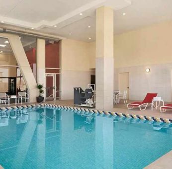 lovely indoor pool with surrounding seating area and sun beds at Homewood Suites by Hilton University City.