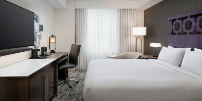 Delux king room with TV, desk, and natural light at Courtyard San Diego Downtown.