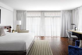 King bedroom with desk, chair, and natural light at St Gregory Hotel.