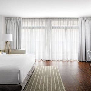 King bedroom with desk, chair, and natural light at St Gregory Hotel.