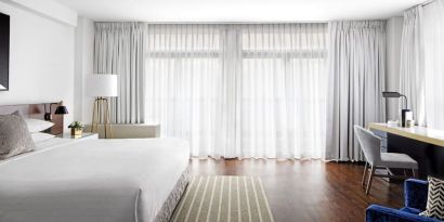 King bedroom with desk, chair, and natural light at St Gregory Hotel.