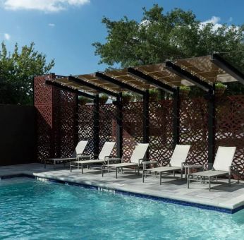 Stunning outdoor pool with pool chairs at Courtyard By Marriott Houston Heights/I-10.