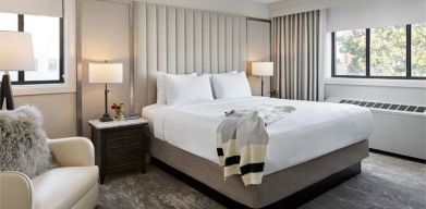 Delux king bed with chair and natural light at Capitol Hill Hotel.