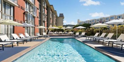 Stunning outdoor pool with sun beds and umbrellas at Hotel Caza.