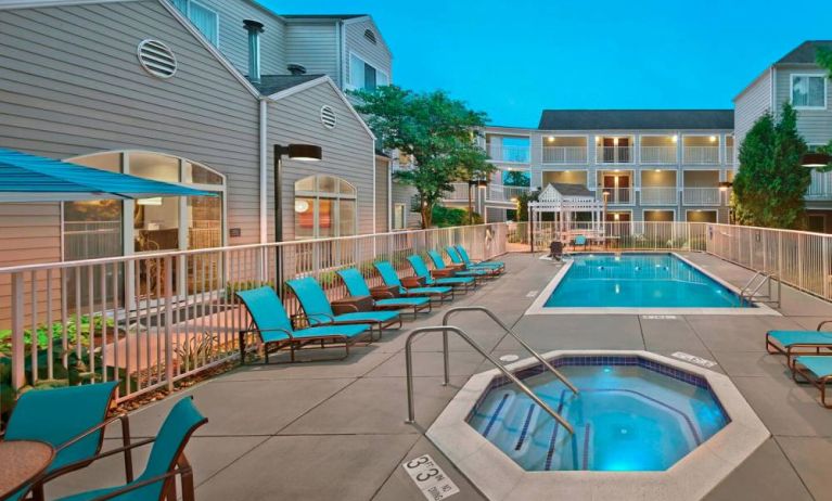 Outdoor pool with lounge chairs at Residence Inn Boston Tewksbury.
