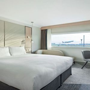 King bedroom with work desk and natural light at Hyatt Place London Heathrow Airport.