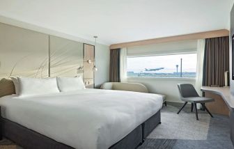 King bedroom with work desk and natural light at Hyatt Place London Heathrow Airport.