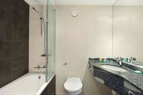 Private guest bathroom with shower and bath at Hyatt Place London Heathrow Airport.