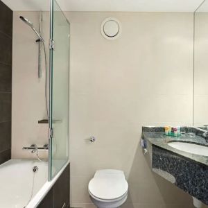 Private guest bathroom with shower and bath at Hyatt Place London Heathrow Airport.