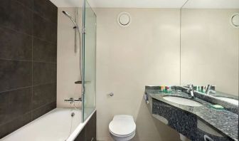 Private guest bathroom with shower and bath at Hyatt Place London Heathrow Airport.