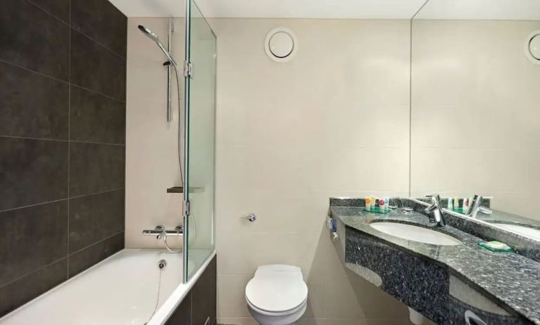 Private guest bathroom with shower and bath at Hyatt Place London Heathrow Airport.