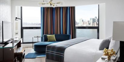 Spacious king bed with TV and seating area at Graduate New York.