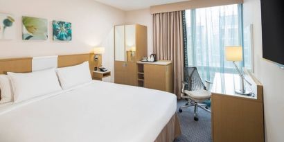 King bed with natural light and work desk at Hilton Garden Inn Bristol City Centre.