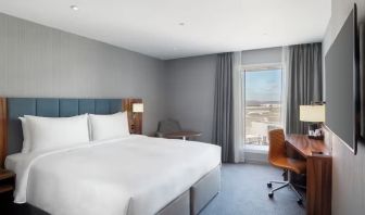 King bed with TV and work station at Hilton Garden Inn London Heathrow Terminals 2 And 3.