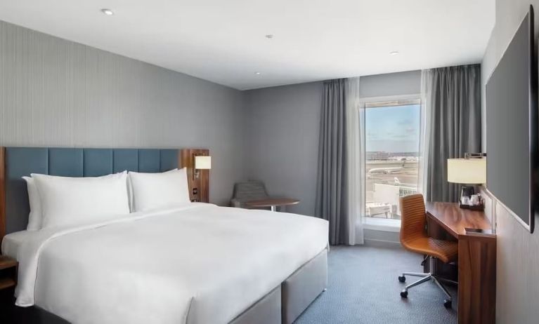 King bed with TV and work station at Hilton Garden Inn London Heathrow Terminals 2 And 3.