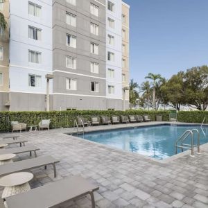 Loungers beside outdoor pool at Homewood Suites By Hilton Miami Airport-Blue Lagoon.