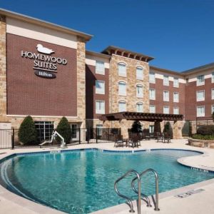 Lovely outdoor pool with seating area at Homewood Suites By Hilton Denton.