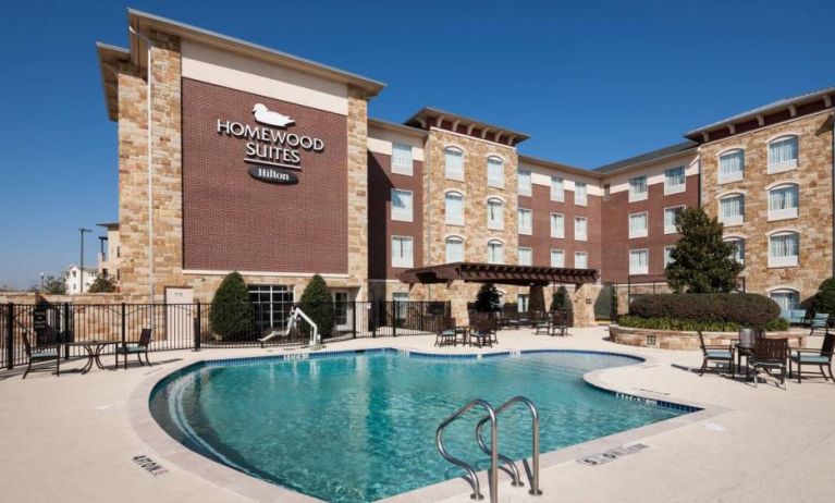 Lovely outdoor pool with seating area at Homewood Suites By Hilton Denton.