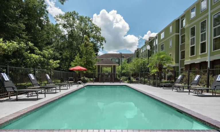 Large outdoor pool with pool chairs at Homewood Suites By Hilton Lafayette-Airport, LA.