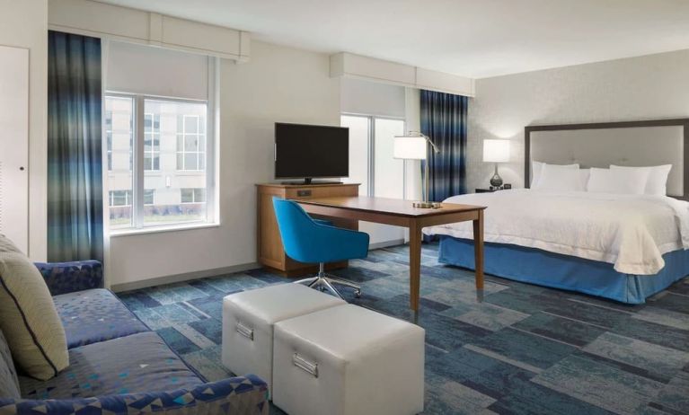 Spacious delux king bed with lounge area at Hampton Inn & Suites Rosemont Chicago O'Hare.