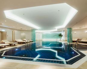Stunning indoor pool with pool chairs at Hilton Berlin.