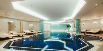 Stunning indoor pool with pool chairs at Hilton Berlin.