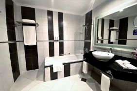 Guest bathroom with shower and bath at Millennium Central Doha.