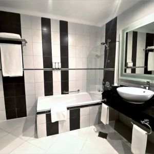 Guest bathroom with shower and bath at Millennium Central Doha.