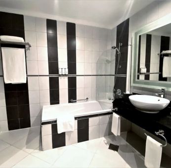 Guest bathroom with shower and bath at Millennium Central Doha.