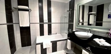 Guest bathroom with shower and bath at Millennium Central Doha.