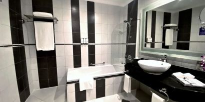 Guest bathroom with shower and bath at Millennium Central Doha.