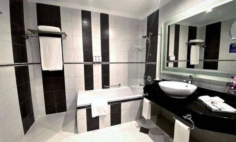 Guest bathroom with shower and bath at Millennium Central Doha.