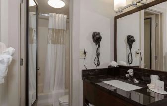 Guest bathroom with shower, bath, and hair dryer at Ramada By Wyndham Boston.