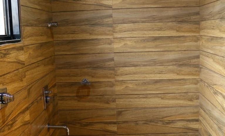 Guest bathroom with shower and towels at Hotel Alka Residency.