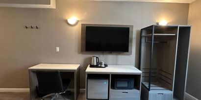 Dayroom with TV, mini-fridge, and work space at Regal Inn & Suites New York.