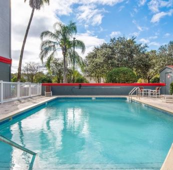 Outdoor pool with seating area at OYO Townhouse Orlando West.