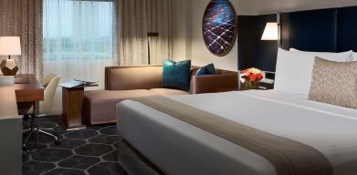 Royal Sonesta Houston Galleria double bed day room, featuring corner sofa and workspace desk and chair.