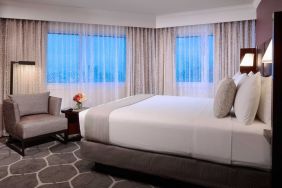 Royal Sonesta Houston Galleria king bed guest room, including windows, armchair, and coffee table.