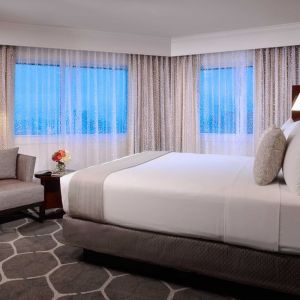 Royal Sonesta Houston Galleria king bed guest room, including windows, armchair, and coffee table.