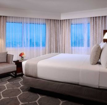 Royal Sonesta Houston Galleria king bed guest room, including windows, armchair, and coffee table.