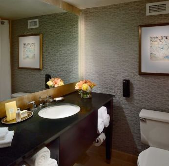 Guest bathroom in Royal Sonesta Houston Galleria, with lavatory, sink, and wide mirror.