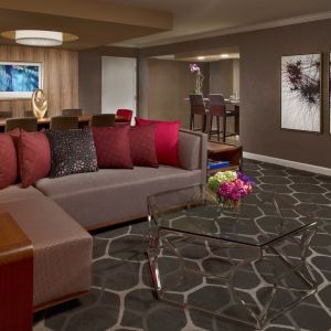 Royal Sonesta Houston Galleria workspace, featuring corner sofa and coffee table, plus long table surrounded by chairs.