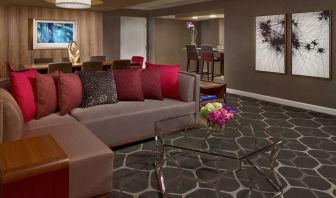 Royal Sonesta Houston Galleria workspace, featuring corner sofa and coffee table, plus long table surrounded by chairs.