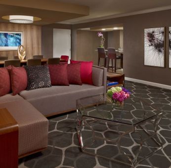 Royal Sonesta Houston Galleria workspace, featuring corner sofa and coffee table, plus long table surrounded by chairs.