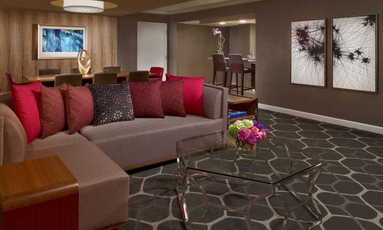 Royal Sonesta Houston Galleria workspace, featuring corner sofa and coffee table, plus long table surrounded by chairs.