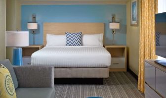 Sonesta ES Suites Tucson guest room, furnished with deluxe king bed, sofa, and television.