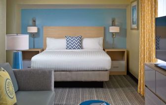 Sonesta ES Suites Tucson guest room, furnished with deluxe king bed, sofa, and television.
