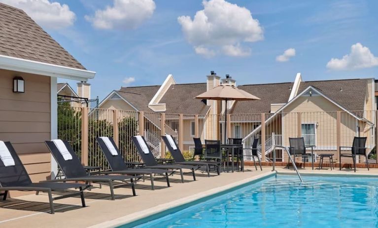 Sonesta ES Suites Tucson’s outdoor pool has a row of sun loungers, plus tables and chairs, by the side.