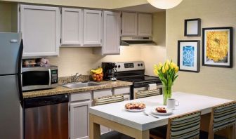 Sonesta ES Suites Tucson guest room kitchen area, equipped with hob, oven, microwave, sink, and fridge freezer, plus dining table.