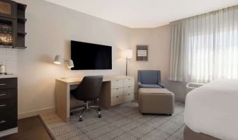 Guest room workspace in Sonesta Simply Suites Irvine East Foothill, furnished with desk, chair, lamp, and television.